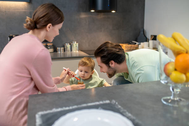 istock Parents feeding a cute baby boy in the kitchen 1404906477