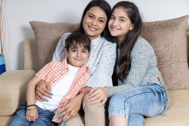 istock Indian Mother kids sitting at sofa looking toward the camera 1404907234