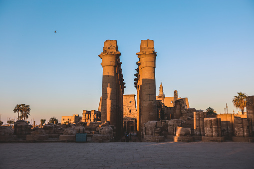 Sunset View to an Illuminated in Yellow Grand colonnade of large Ancient Egyptian temple in Luxor, Egypt
