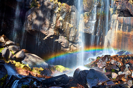 Waterfall in the foreground with a rainbow and large rocks wet with moss in mexiquillo Durango in the Sierra Madre Occidental