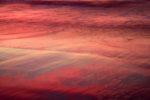 Texture of sand and sea reflecting red and purple colors with sweeping effect in Mazatlan Sinaloa