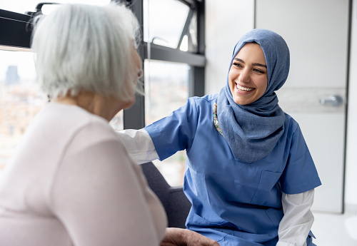 Muslim nurse talking to a senior patient at the hospital