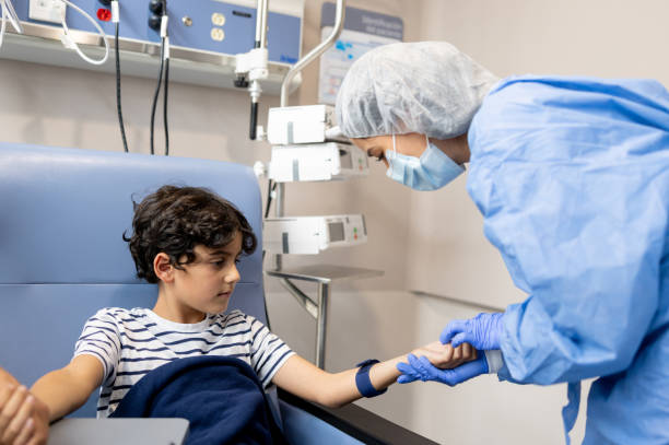 menino em quimioterapia olhando para uma enfermeira encontrando uma veia em seu braço - outpatient - fotografias e filmes do acervo