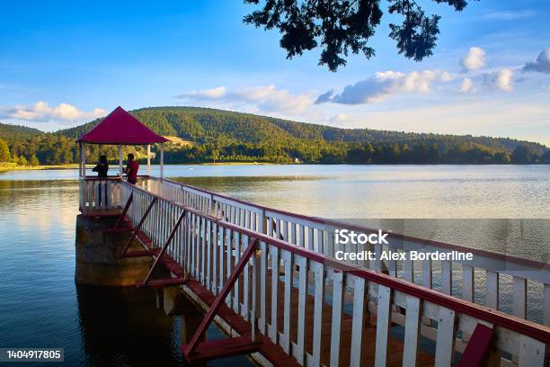 People At The Viewpoint Of A Pier In The Middle Of A Lake At Sunset With Mountains In The Background At The Brockman Dam In El Oro State Of Mexico Stock Photo - Download Image Now