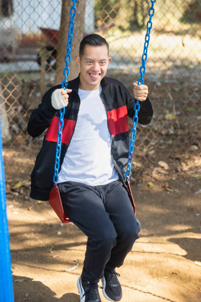 Boy with down syndrome playing on the swings at school