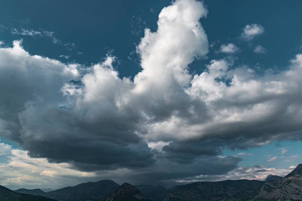 Scenic rain clouds over mountain tops. Bug cumulus clouds on the deep blue sky.