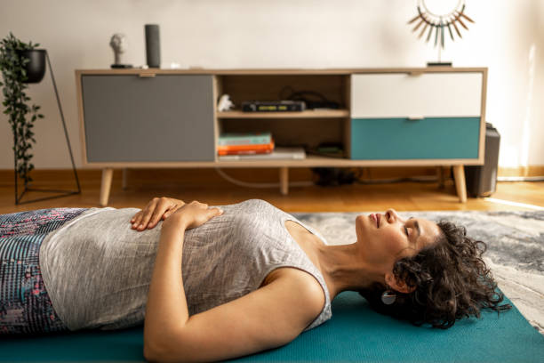 Woman doing breathing exercises A woman lies on yoga mats and does breathing exercises yoga pants stock pictures, royalty-free photos & images
