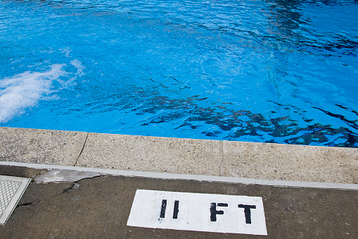 Poolside depth marker at deep end of swimming pool.