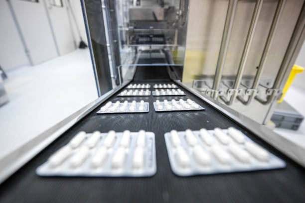 Capsule pills in blister pack on conveyor belt in a pharmaceutical industry production stock photo
