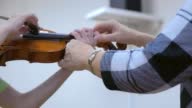 istock Music teacher teaches child to play violin in musical school, hands closeup. 1404943576