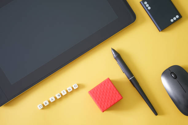 istock Stylus and graphics tablet for drawing on yellow background, next to an external ssd, computer mouse, red gift box and the inscription drawing. Modern creativity and computer technologies. 1404944912