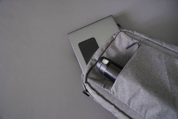 istock A small textile backpack or bag, along with a small camping thermos, a gray laptop or ultrabook, and a smartphone. Gray background. Traveling and trip with gadgets. Copy cpace. 1404944964
