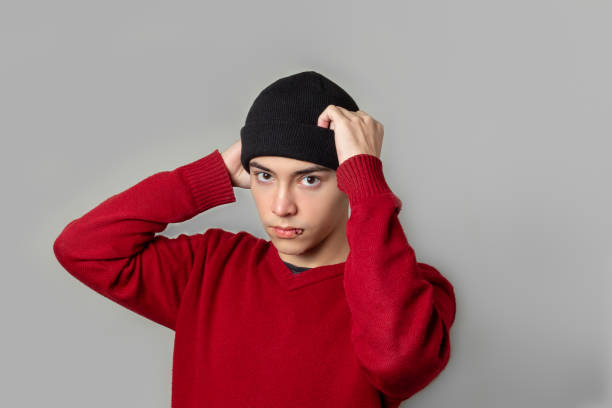 A young man in a cold weather cap and a red sweater looking at the camera.