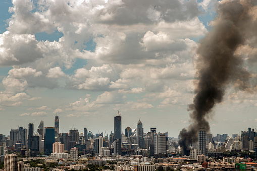 Bangkok, Thailand - 21 Jun, 2022 : Plume of black smoke clouds from burnt building on fire at community area in the bangkok city. Fire disaster accident, No focus, specifically.
