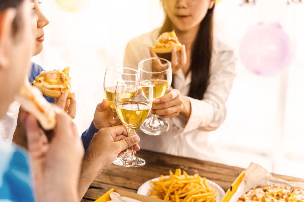 Multi-ethnic Asian groups of international students chat and make friends during a pizza party. Hungry male and female employees share lunch in a coworking space.