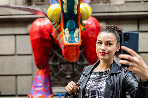 Business woman taking a selfie with an orange alebrije in Mexico City