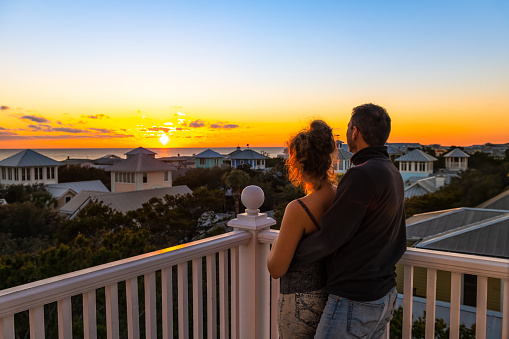 High angle view on colorful sunset paradise with young couple woman man watching looking at view on Gulf of Mexico in Seaside, Florida on rooftop terrace building house balcony