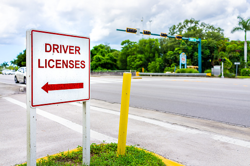 Naples, Florida downtown street empty road with roadside sign signpost for directions to driver license office for renewal or people who relocated