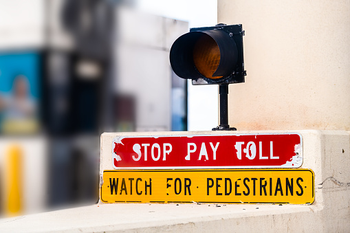 Red stop pay for toll watch for pedestrians sign text light on road interstate highway from Miami to Naples, Florida