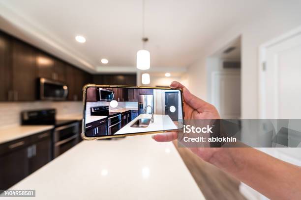 Hand Photographing House Apartment Kitchen Island Room For Sale Or Rent With Phone Smartphone Closeup Point Of View In Modern Luxury Condo Home Tour With Blurry Bokeh Background Stock Photo - Download Image Now