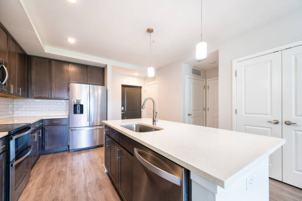 istock Empty vacant kitchen open plan modern apartment with sink faucet quartz countertop island by new French door fridge refrigerator wood cabinets and recessed ceiling lamp lights 1404958843