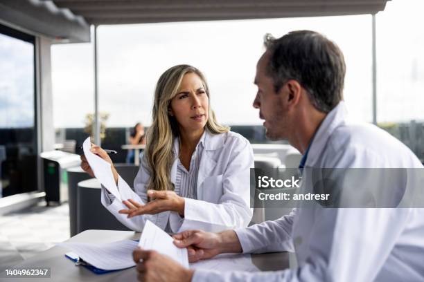 Team Of Doctors Discussing A Medical Chart Stock Photo - Download Image Now - Civilian, Healthcare And Medicine, 30-34 Years