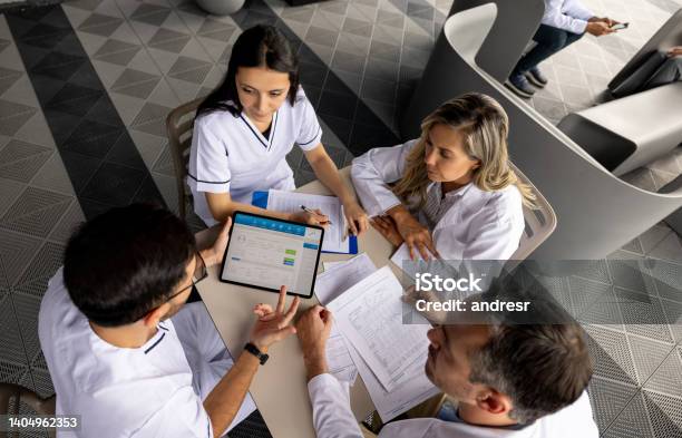 Group Of Healthcare Workers In A Meeting Dicussing A Patients Diagnosis Stock Photo - Download Image Now