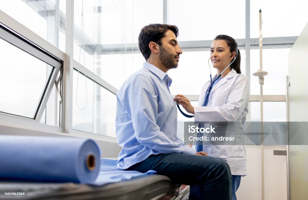 Female doctor examining a patient at her office Latin American female doctor examining a patient at her office and listening to his heart with a stethoscope Medical Exam Stock Photo