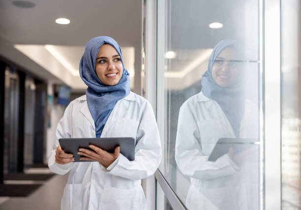 Happy Muslim doctor working at the hospital using a tablet stock photo