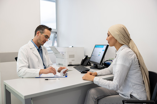 Oncologist talking to a female patient during a consultation at his office - healthcare and medicine