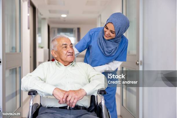 Muslim Nurse Taking Care Of A Senior Patient In A Wheelchair Stock Photo - Download Image Now