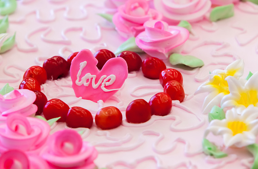 Valentine cake in form of heart with whipped pink cream, decorated with strawberries, blueberries and blackberry on white background. Picture for a menu or a confectionery catalog.