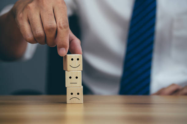 istock Closeup hands holding smiley face icon on wooden cube. 1404971141