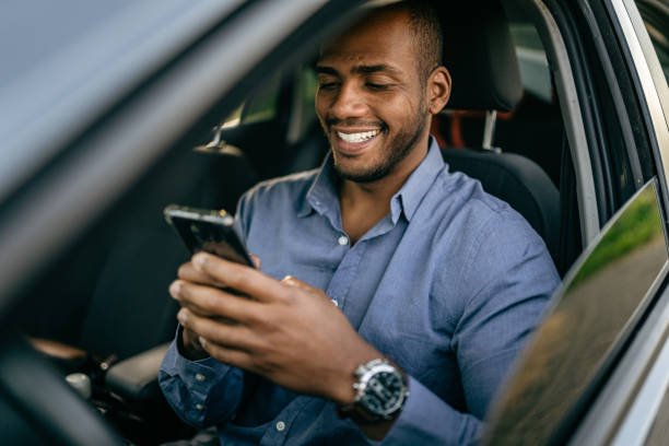 uomo che usa lo smartphone in auto parcheggiata - car driving men business foto e immagini stock