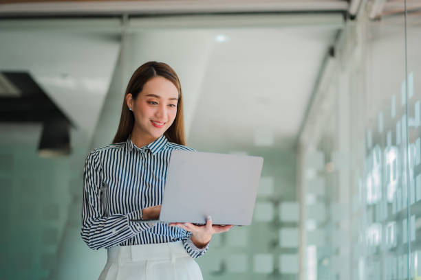 istock asian women smiling standing with laptop working on blurred background 1404978544