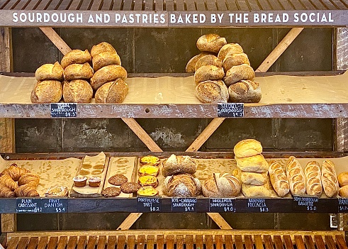 Horizontal still life of fresh baked bread loaves and pastries on shelves in rural country bakery Australia