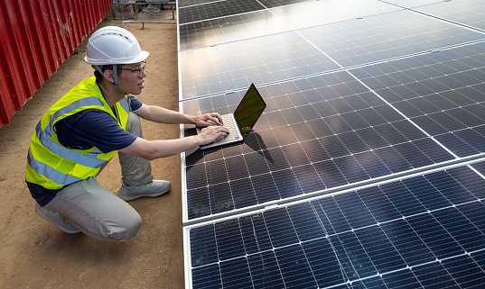 Side view of male electrician using laptop at solar power plant