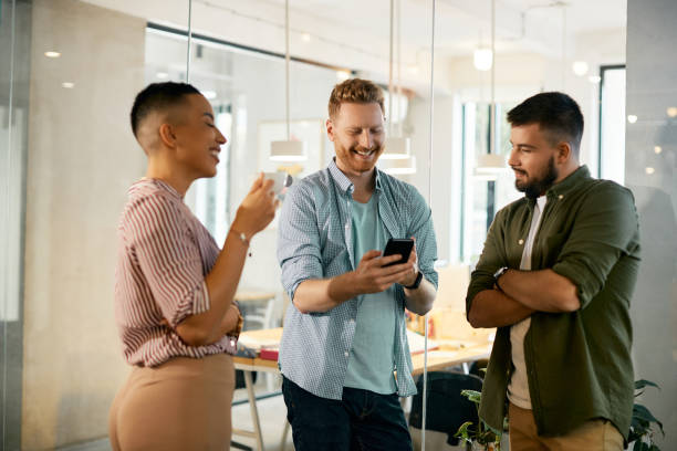 istock Cheerful businessman using mobile phone while having a break with coworkers in the office. 1404987158