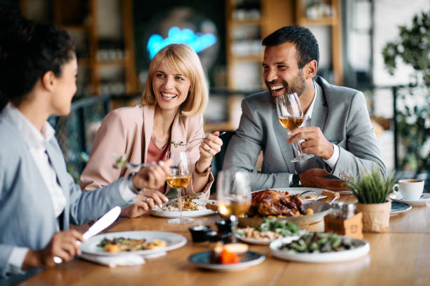 Cheerful coworkers having fun during business lunch in restaurant. Happy business people laughing while talking and having lunch in restaurant. business dinner stock pictures, royalty-free photos & images