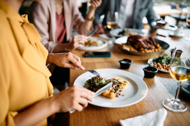 Close up of entrepreneur having business lunch with her coworkers in restaurant. Close up f businesswoman eating lunch with colleagues in restaurant. business dinner stock pictures, royalty-free photos & images