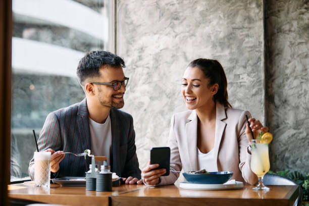 istock Young happy business couple using smart phone while eating in a cafe. 1404990699
