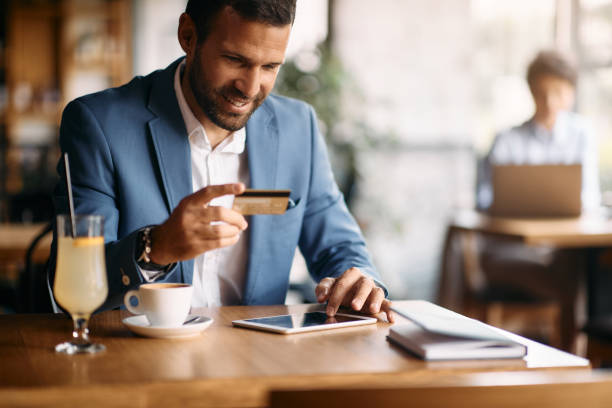 istock Happy businessman using touchpad while online banking in a cafe. 1404991117