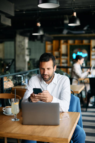 istock Male entrepreneur text messaging on smart phone while working in a cafe. 1404991803