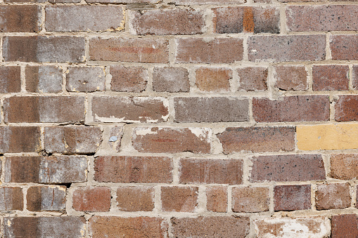 weathered, grungy and dirty bricks in a wall. Structure is regular and cement is used in the gaps.