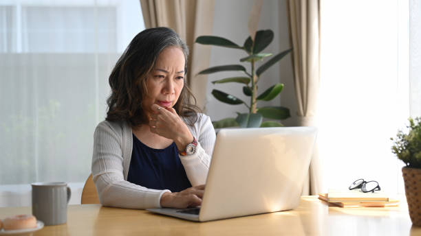 istock Concentrated middle aged woman watching online webinar, working at home with a laptop computer. 1404996451