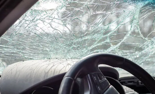 Damaged car window after an accident. Broken windshield as a result of an accident, inside view. Cabin interior details, view from the cab. Safe movement. Broken windshield. Glass crack and damage