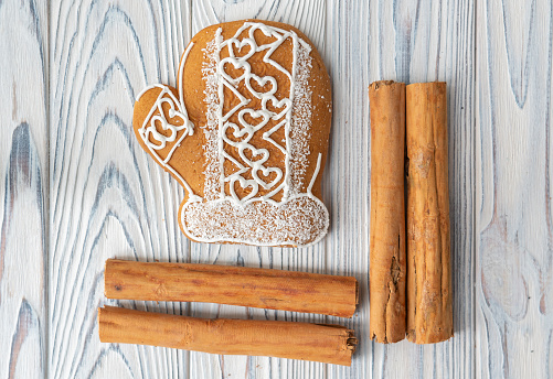Gingerbread spice cookies in form of mitten with hearts and cinnamon sticks