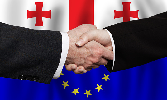 European Union and Georgia concept. Handshake on European and Georgian flags background