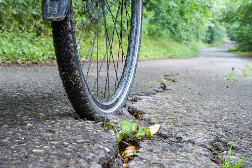 A bicycle tire is stuck in a crack in the asphalt. Bad subsoil on bike paths is the cause of many accidents that occur with bikes.