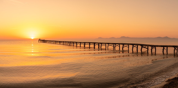 Wooden pier in the beach. Wood bridge in the beach. Sunset in the beach, golden hour. Mallorca island, \